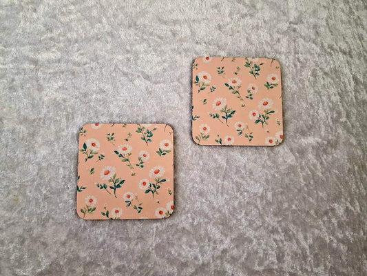 Made By Allie square drink coasters with a peach background and white floral daisy pattern for table protection.